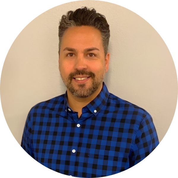Professional headshot of a smiling man wearing a blue plaid shirt.