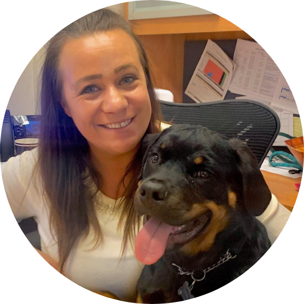 Woman smiling with a Rottweiler outdoors.