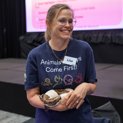 Smiling women, looking off to the side, holding a snake.