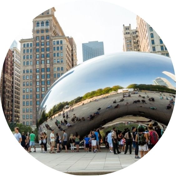 Cloud Gate sculpture in Millennium Park surrounded by visitors and Chicago buildings.