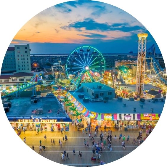 Amusement park and boardwalk glowing with colorful lights at sunset.