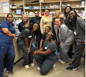 Veterinary care team posing together in a hospital treatment room.