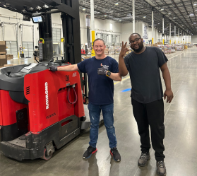 Two people beside forklift in warehouse