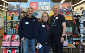 Store staff standing under pet food sign.