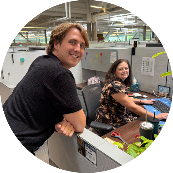 Two people interacting in office cubicle