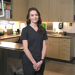 A female practice manager standing in a veterinary examination room while smiling for the camera