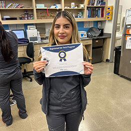 A registered vet tech holding a certificate of completion for the Registered Vet Tech Program