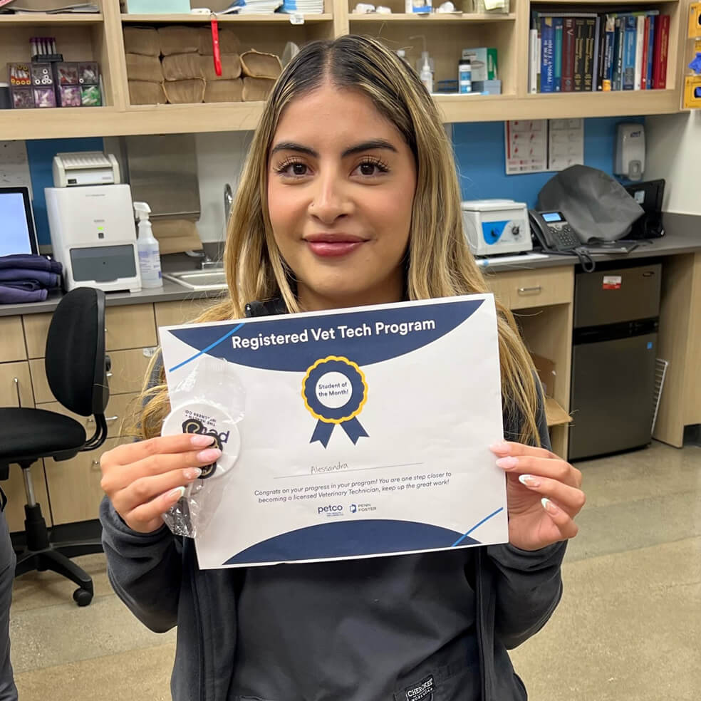 A vet tech holding a certificate of completion for the Registered Vet Tech Program
