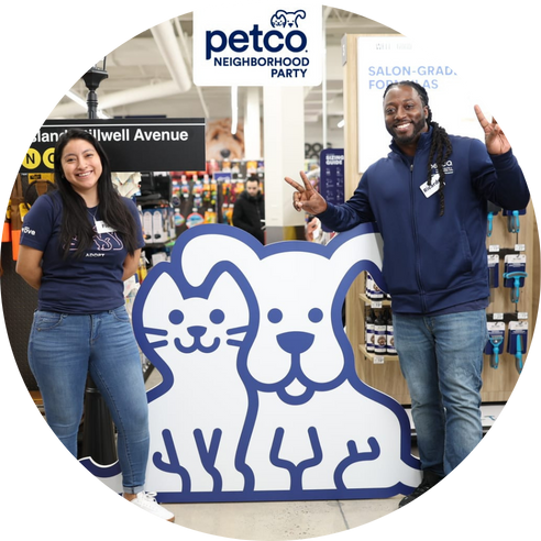 Two store employee standing on either side of a large cutout featuring a cartoon cat and dog.