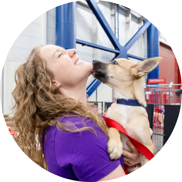 a women holding a dog that's kissing her chin