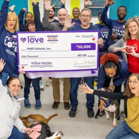 Group of people posing with a large ceremonial check for $50,000 from Petco Love and BOBS from Skechers to PAWS Atlanta, Inc., dated February 2023, with dogs present