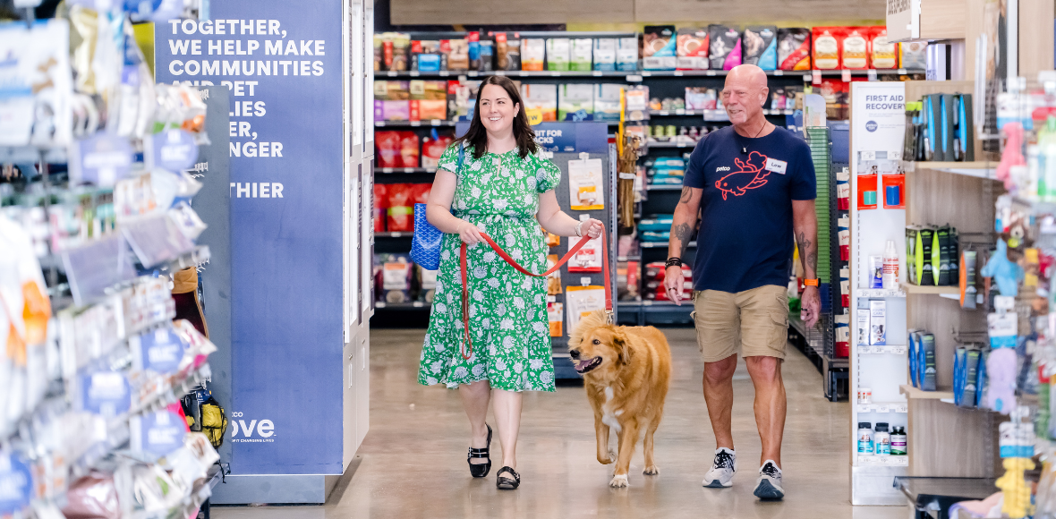 Petco partner walking with a guest and their dog inside a pet care store.