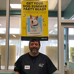 Dave standing in front of window with a sign that says, "Get your dog summer party ready"