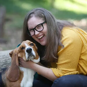 Dr. Abigail Pagel crouching down hugging a basset hound