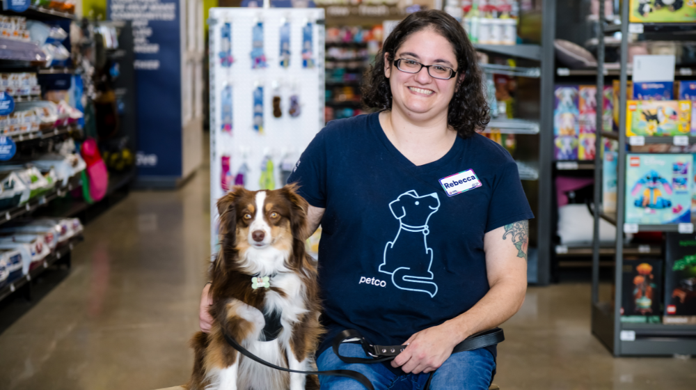 Petco dog trainer smiling with a dog inside a pet care store.