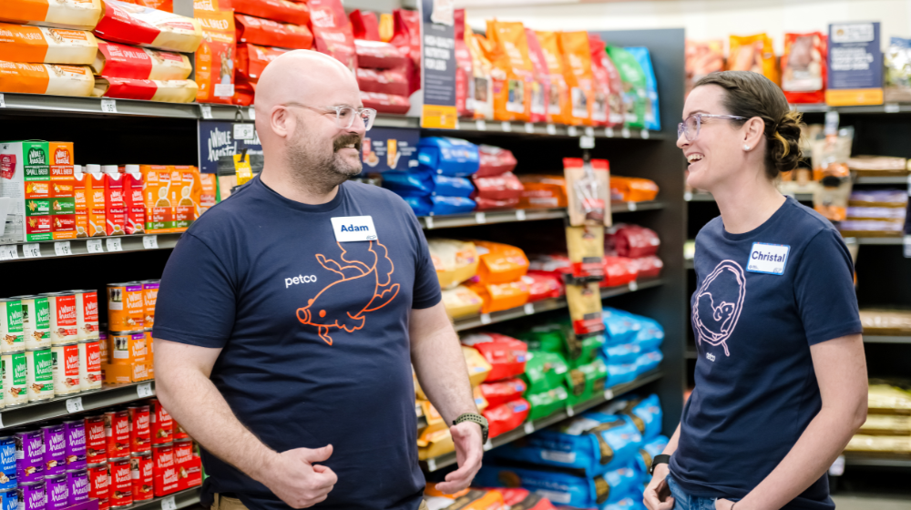 Two Petco leaders talking and smiling together in a pet care store.