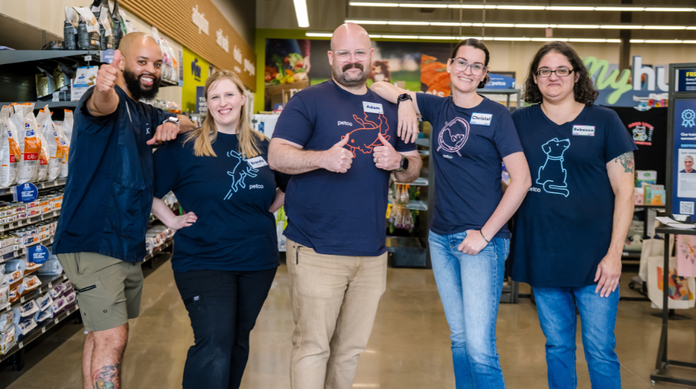 Five Petco partners smiling together inside a pet care store.