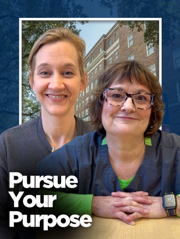 Two women, one in a gray sweatshirt and one in a blue and green layered top, in front of a hospital