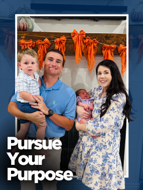 Dark haired women holding baby standing next to a male in a blue shirt holding a toddler.