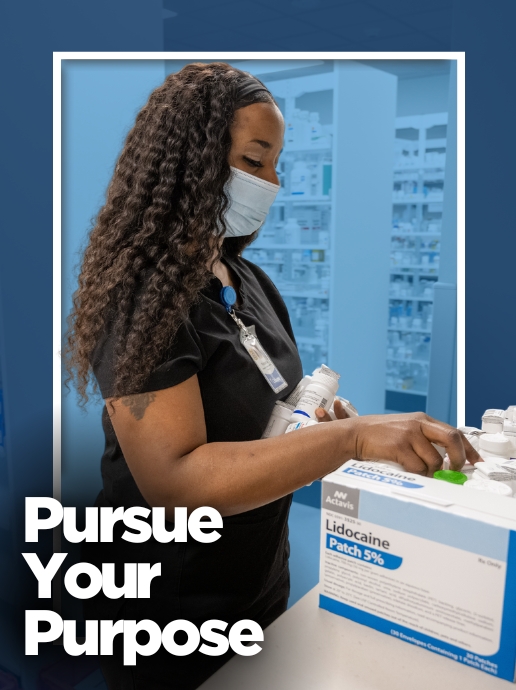 A woman wearing black medical scrubs and a face mask selects medication boxes at a pharmacy workstation. Text reads, "Pursue Your Purpose."