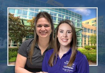 Two women, one in a gray shirt and one in a purple shirt, in front of a hospital