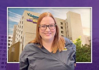 Woman in gray scrubs in front of a hospital