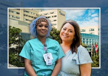 Two women stand in front of a hospital building; one wears green medical scrubs with an ID badge and the other wears a light-colored dress.
