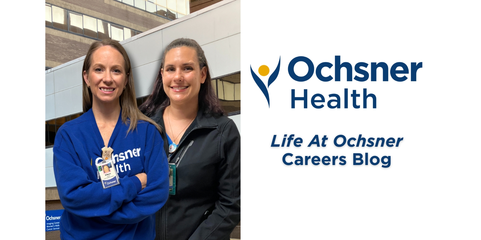 Two smiling women, one in a blue Ochsner Health sweatshirt and the other in a black jacket, stand side-by-side in front of a modern building.