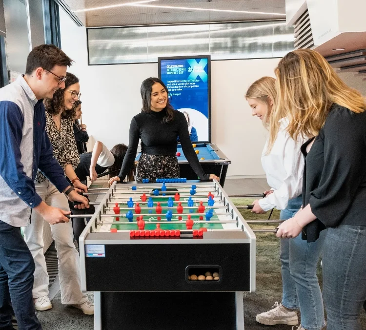 A group of coworkers enjoying a game of foosball together in their office.