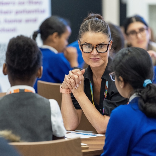 Teacher talking with students in a classroom discussion.