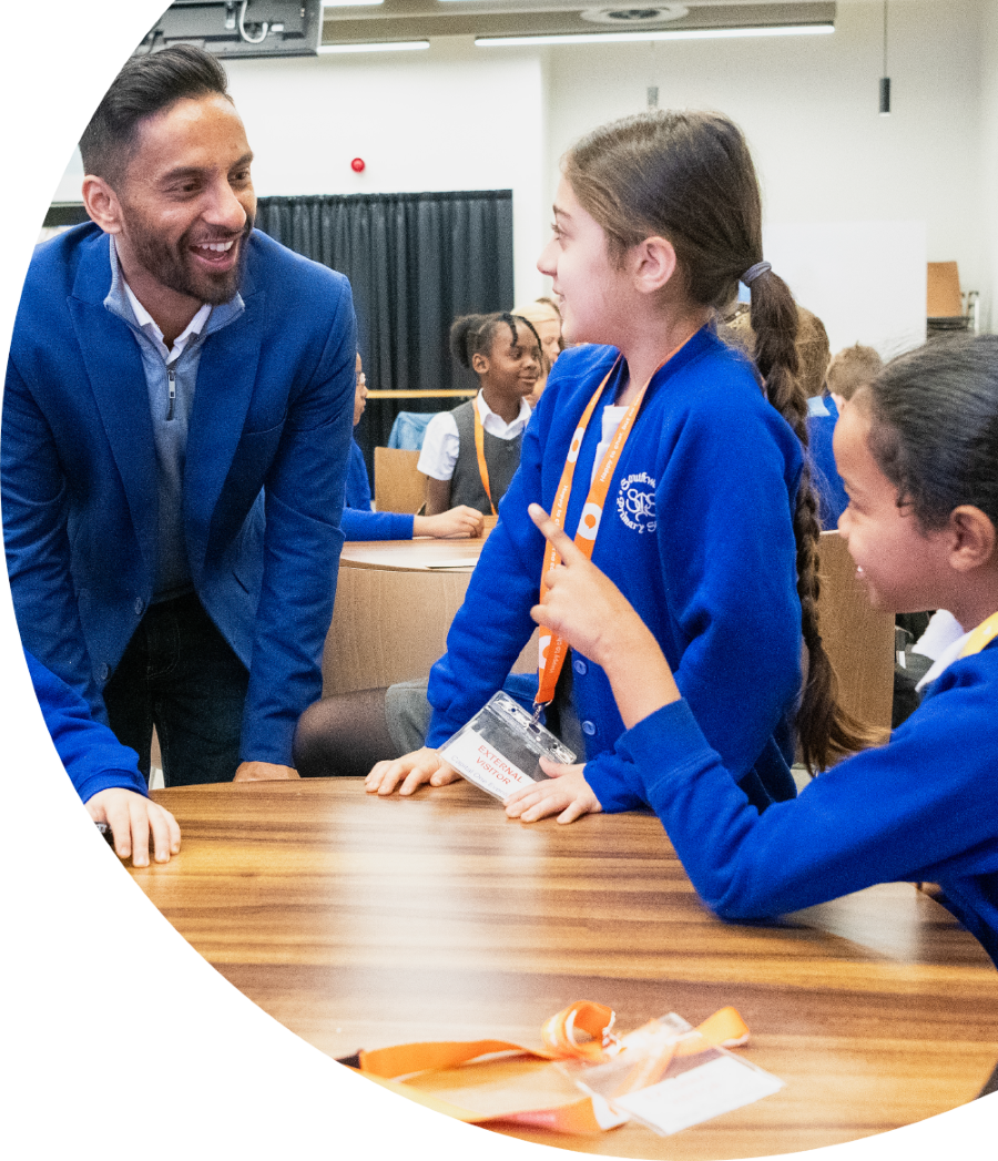 Teacher talking and smiling with young students in class.