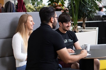 Team chatting and smiling in a bright office space.