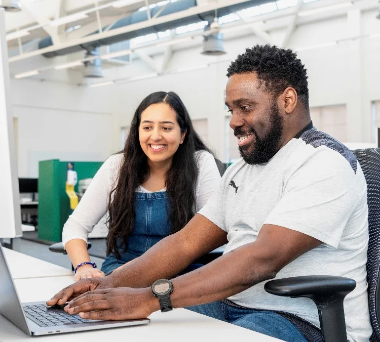 A man and women smiling and working together at a computer.