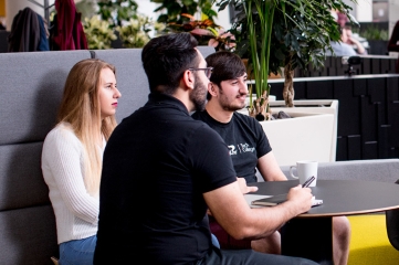 Team chatting and smiling in a bright office space.