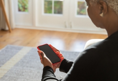 A woman holding a red smartphone indoors.