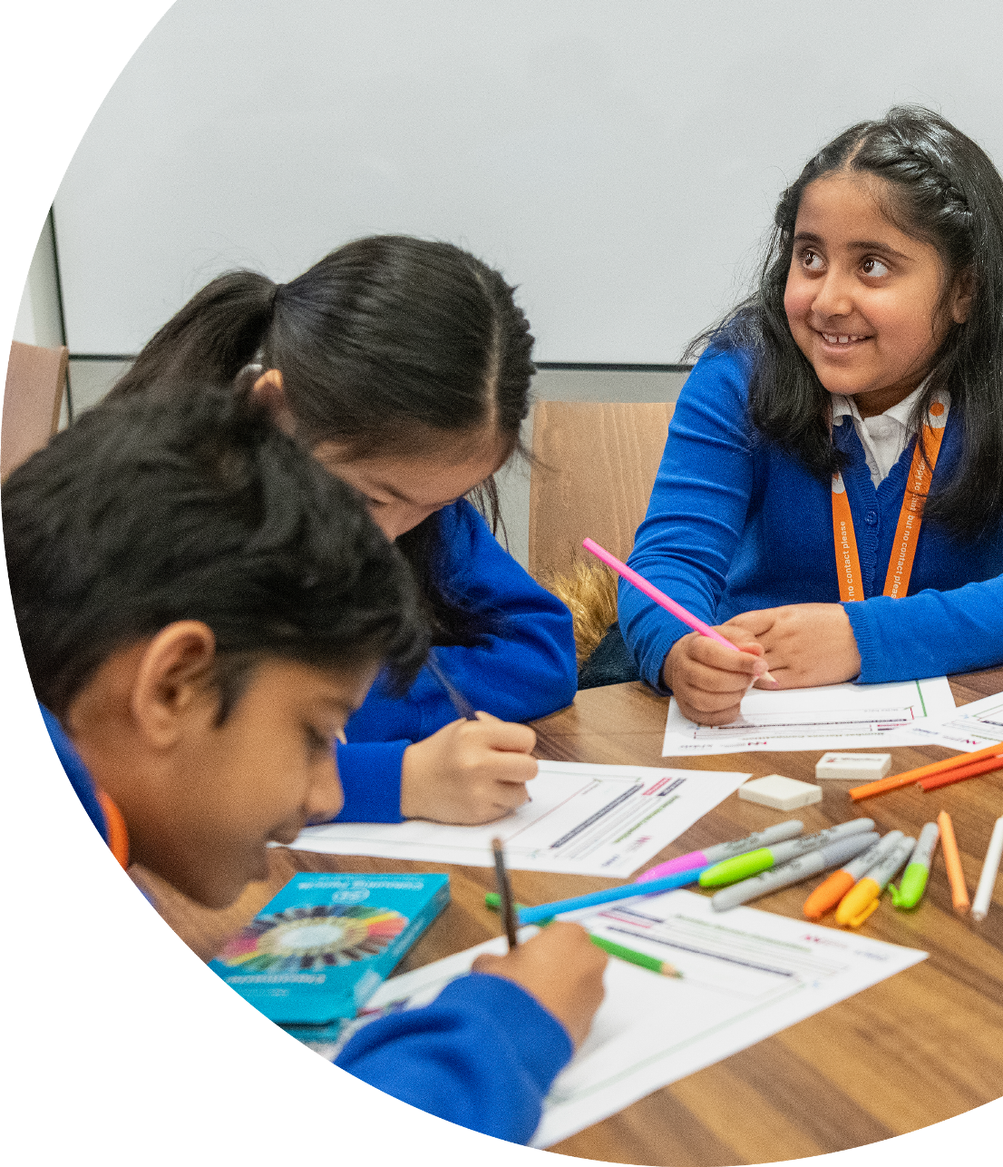 Children in blue uniforms drawing with colored pencils.