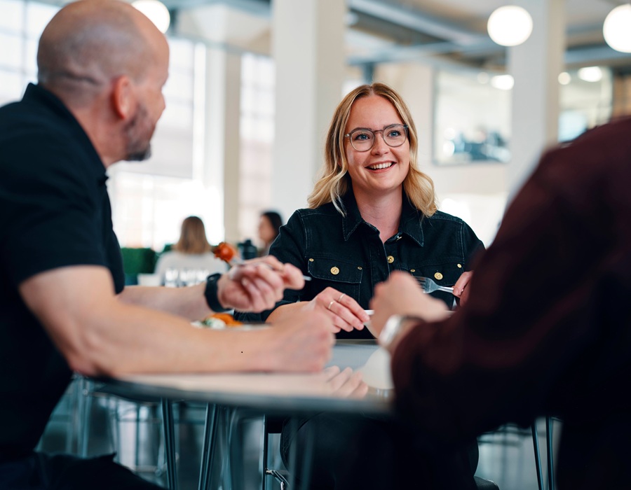 Smiling woman chats with coworkers at a lunch table