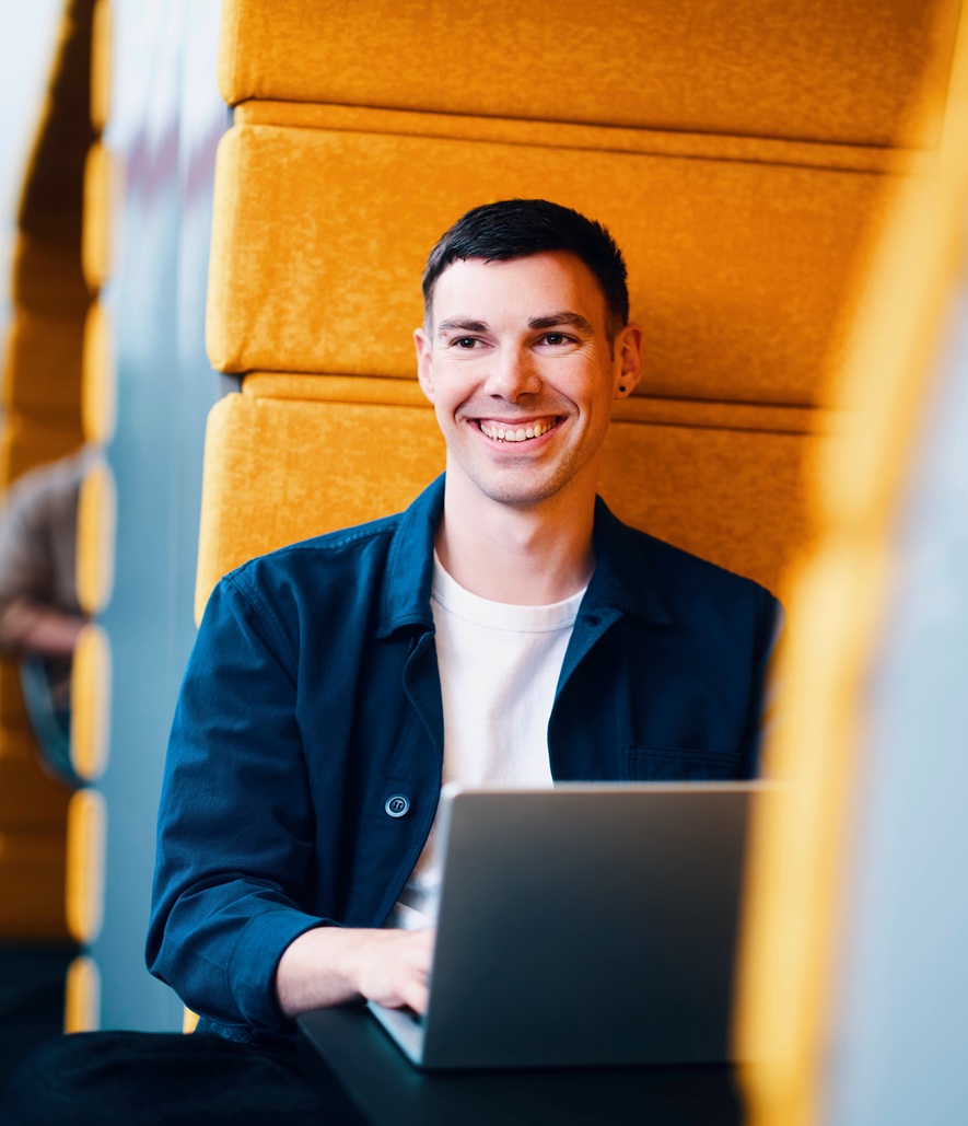 Smiling man working on laptop in modern office