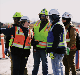 Safety-equipped workers discussing project on construction site