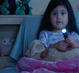 Young girl in bed with flashlight on