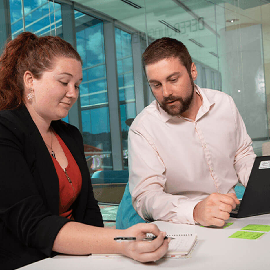 Male and female employee looking at a notepad