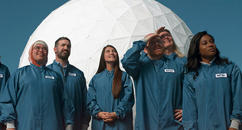 Group of employees standing together looking at something in the sky