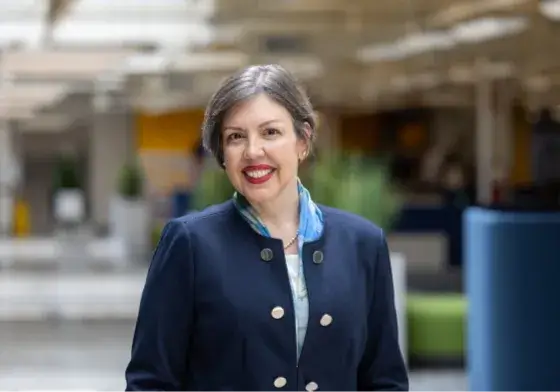 Female employee standing inside of a building while smiling for a picture