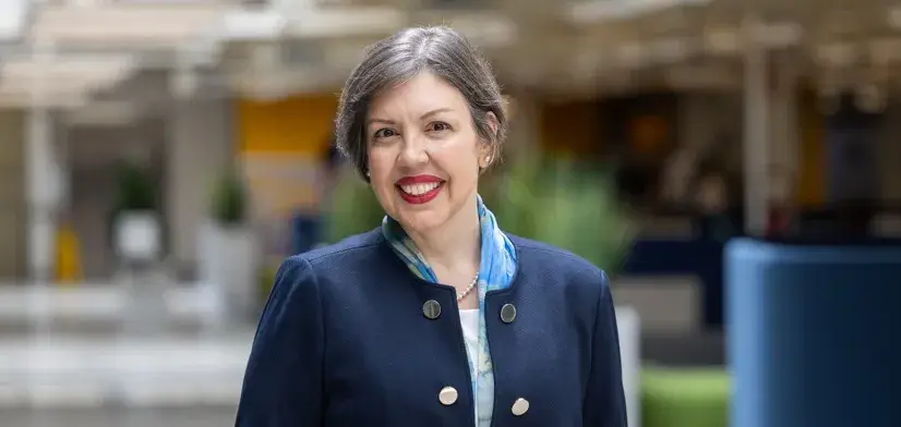 Female employee standing inside of a building while smiling for a picture