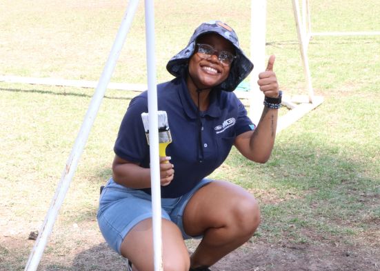 Smiling woman holding a paint brush and giving a thumbs up