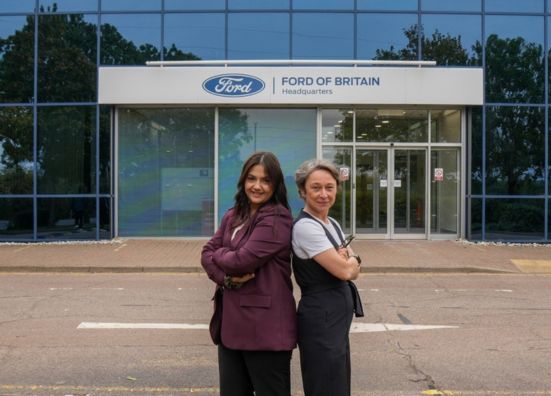 Two Ford employees standing in front of the Ford of Britain headquarters