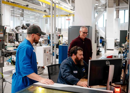 Ford employees working together while viewing something on a computer screen.