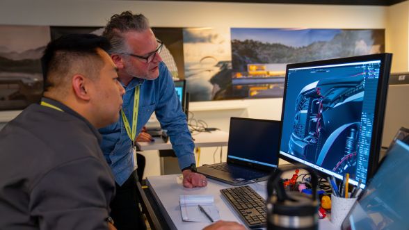 Two Ford employees discussing vehicle design while looking at images on a computer
