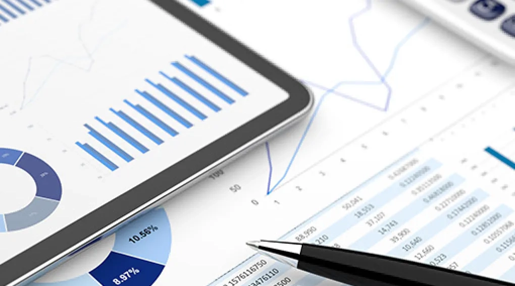 Financial charts, tablet, and pen on a desk