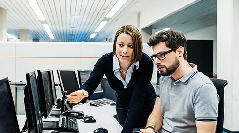 Woman helping a man with computer setup in an office